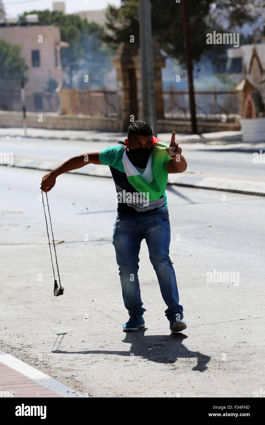 A masked Palestinian youth holds a homemade slingshot in his hand