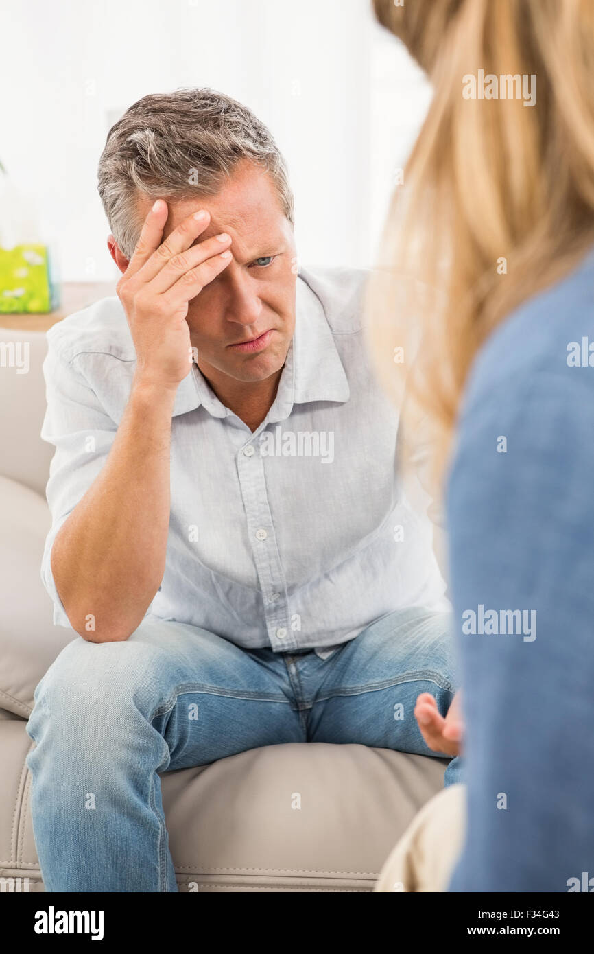 Worried man sitting on couch and talking to therapist Stock Photo
