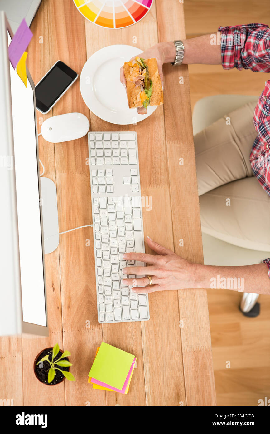 Casual designer working with computer and eating sandwich Stock Photo ...