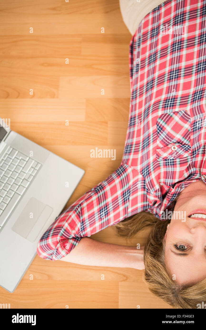 Smiling woman lying on floor next to laptop Stock Photo - Alamy