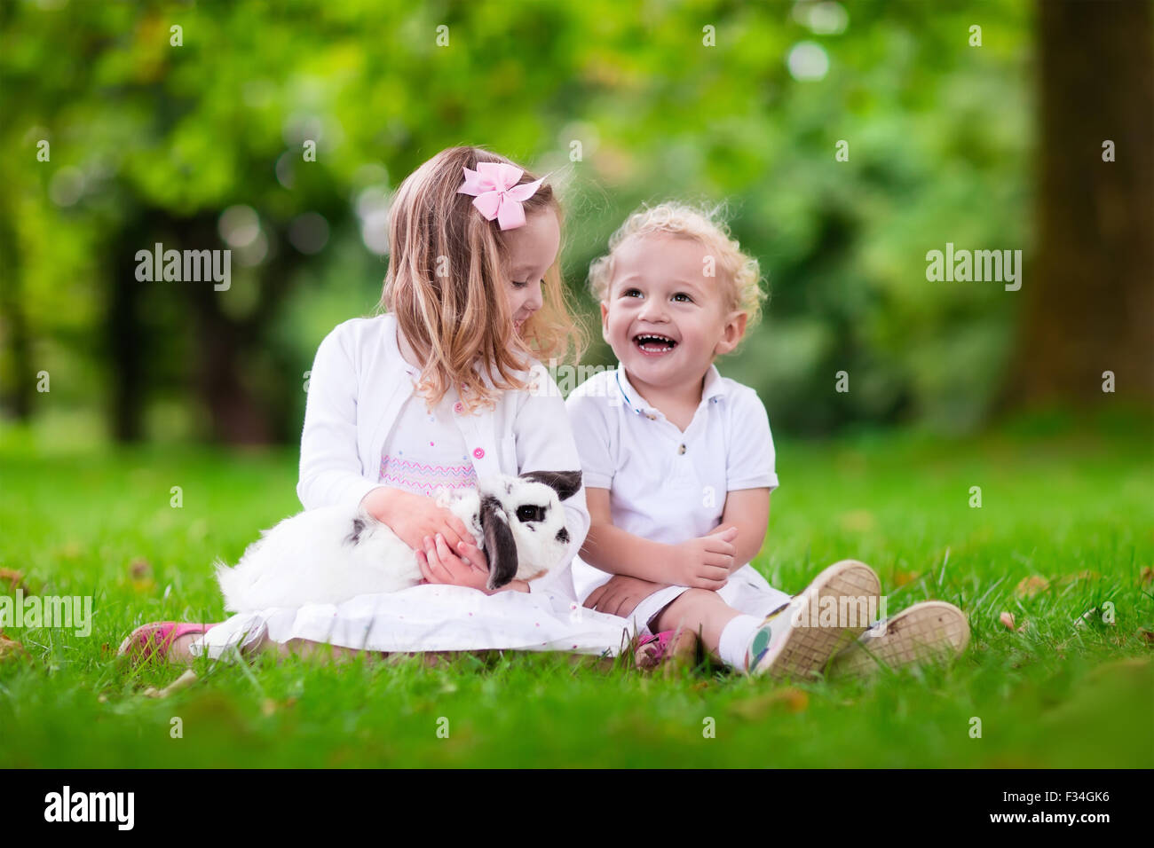 Children play with real rabbit. Brother and sister at Easter egg hunt