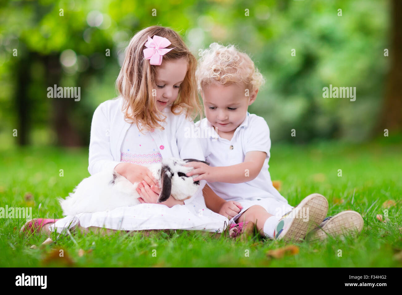 Children play with real rabbit. Brother and sister at Easter egg hunt
