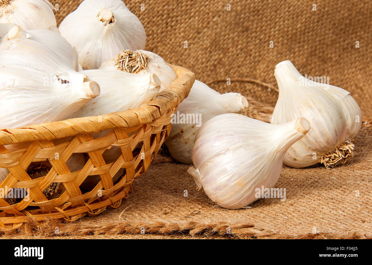 Whole head of garlic in a wicker basket on sackcloth Stock Photo