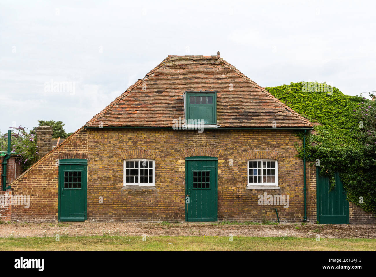Deal Castle, Napoleonic War military storehouse opposite the castle. A one storey with roof attic brick building with green wooden doors. Stock Photo