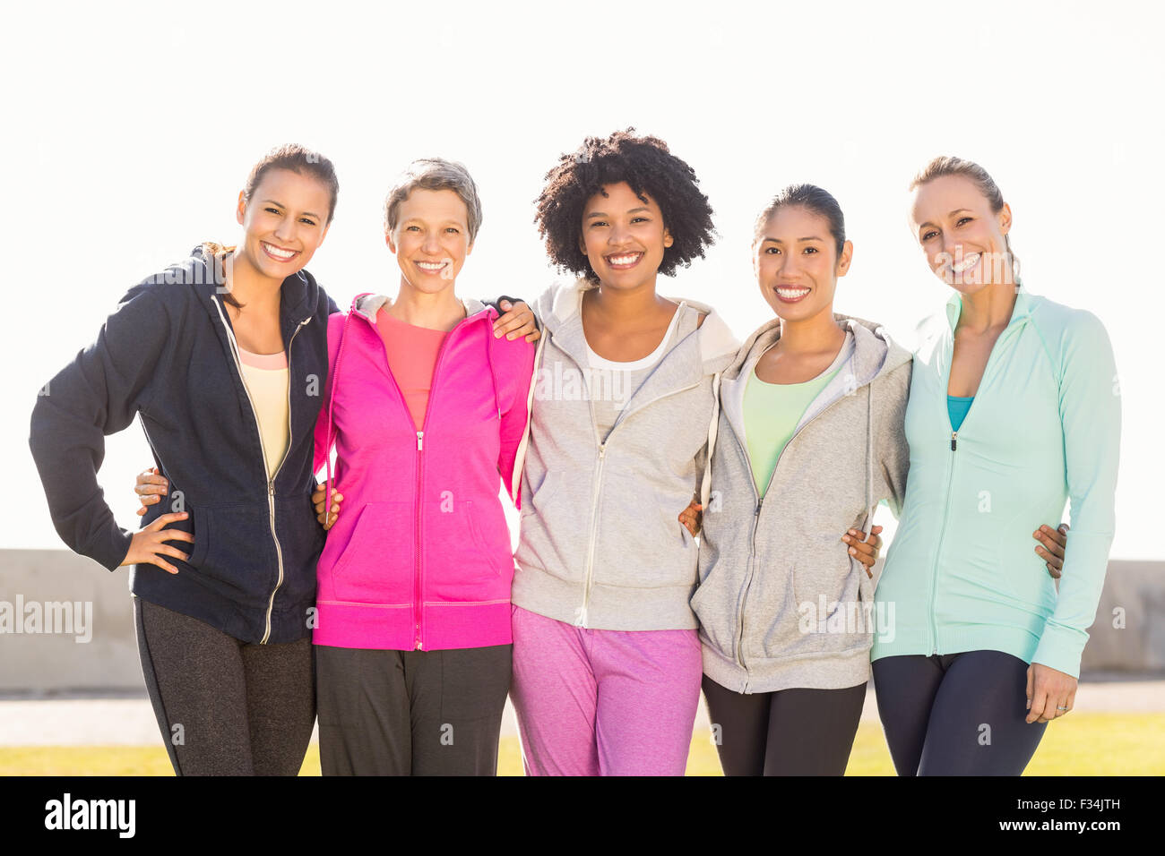 Smiling sporty women with arms around each other Stock Photo - Alamy
