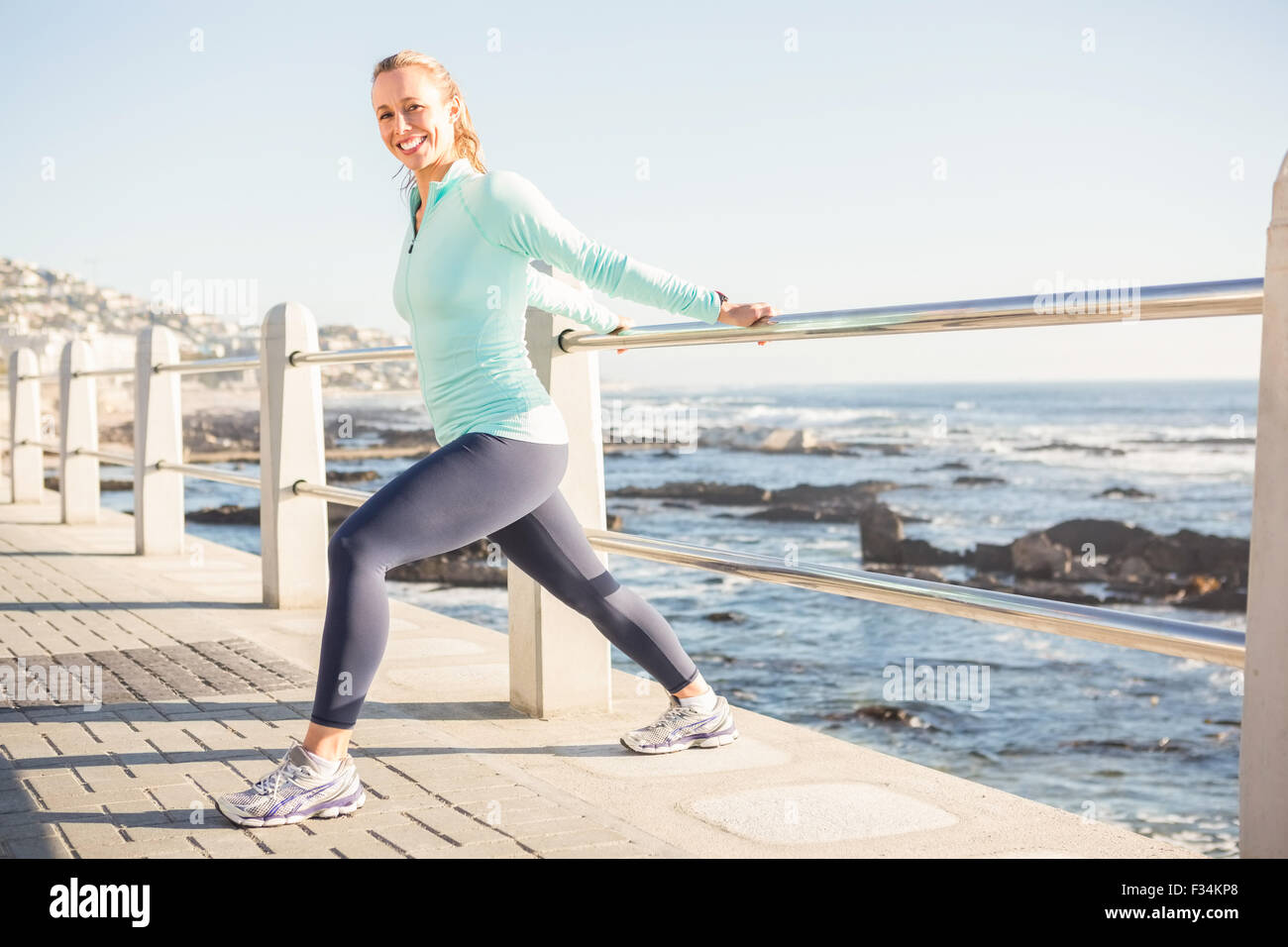 Smiling fit blonde stretching on railing Stock Photo - Alamy
