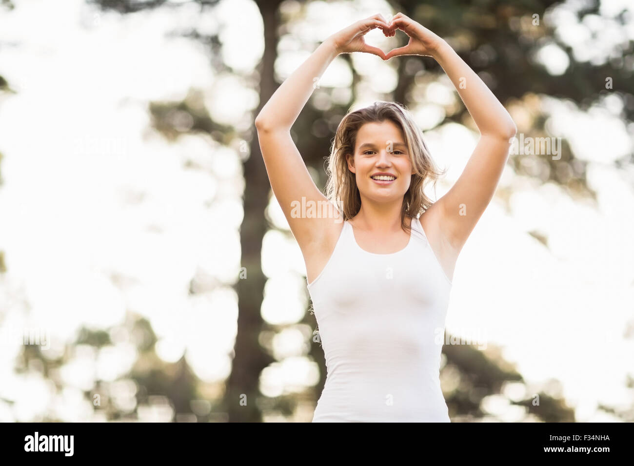 Pretty young jogger shaping heart with hands Stock Photo