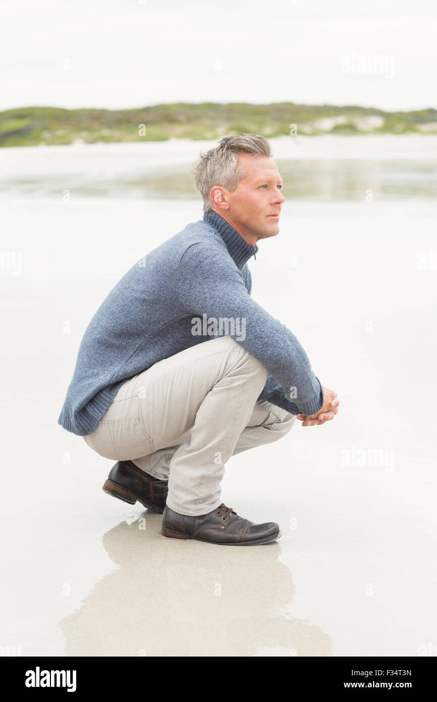 Man crouched down at the shore Stock Photo