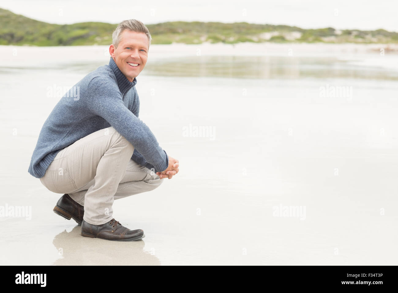 Man crouched down at the shore Stock Photo - Alamy