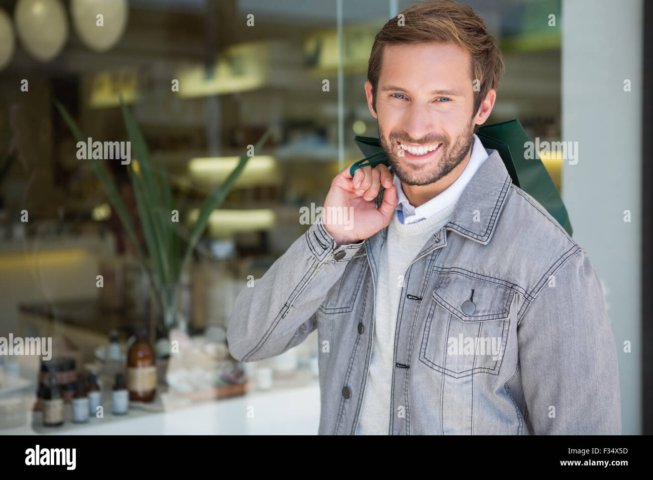 Young happy smiling man holding shopping bags Stock Photo - Alamy