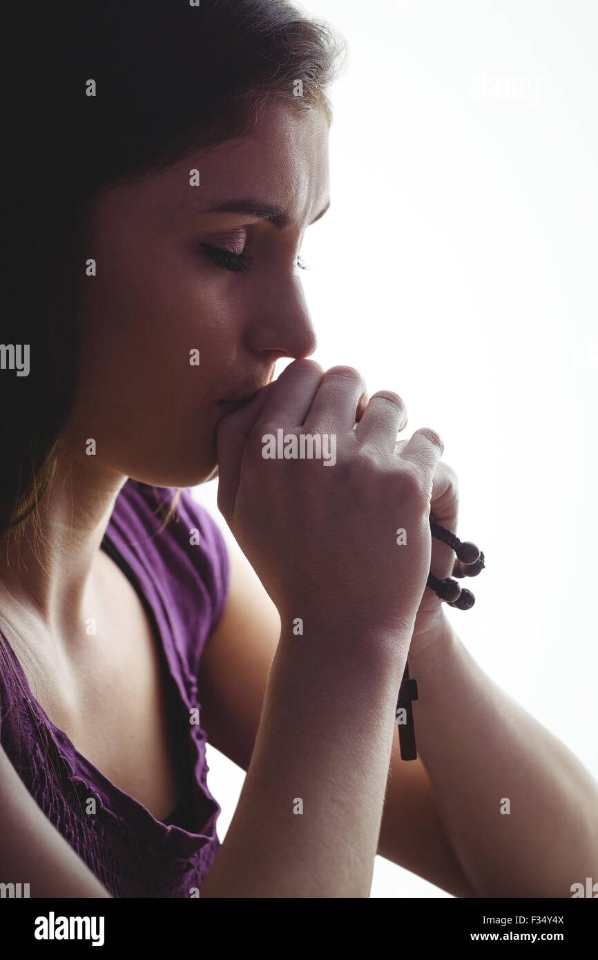 Woman praying with wooden rosary beads Stock Photo