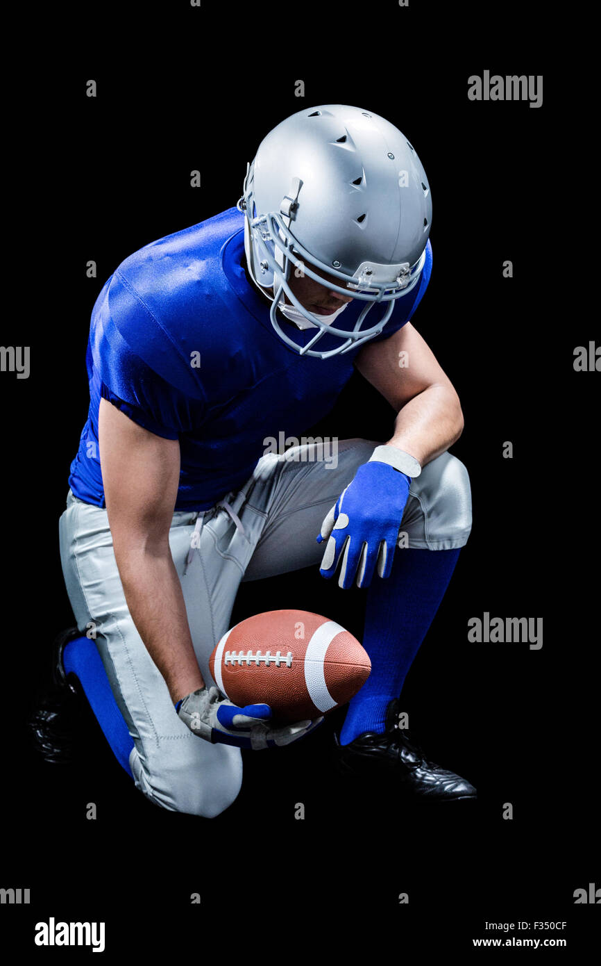 American football player kneeling while holding ball Stock Photo Alamy