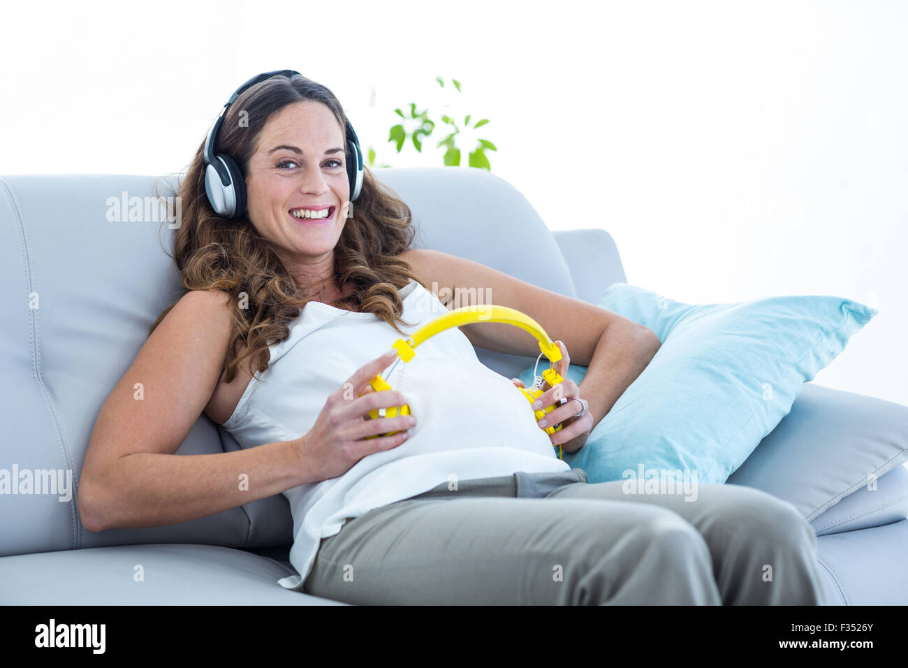 Pregnant woman listening to music in living room Stock Photo - Alamy