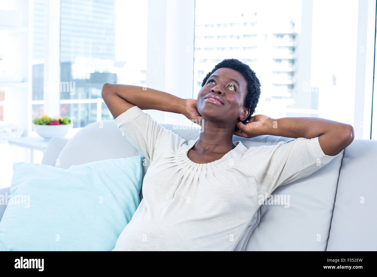 Woman looking up while relaxing on sofa at home Stock Photo - Alamy