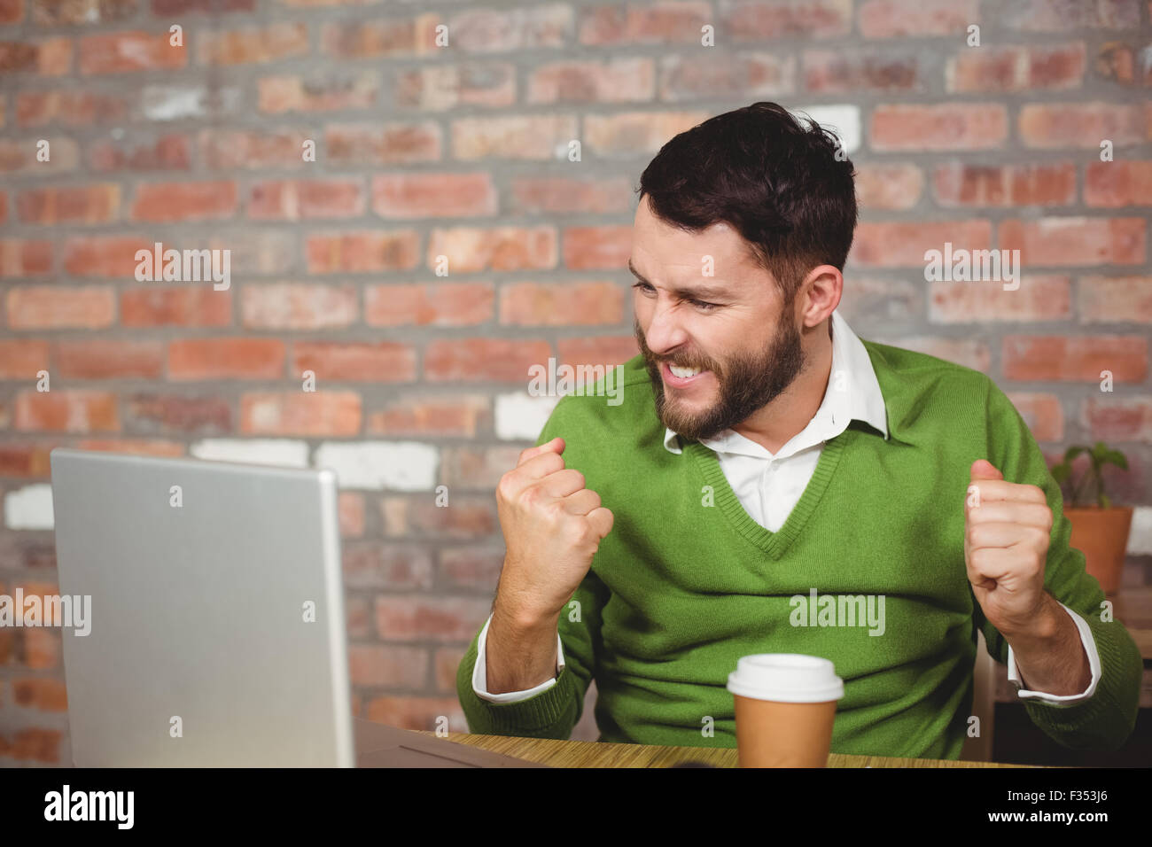 Excited businessman clenching fist in office Stock Photo