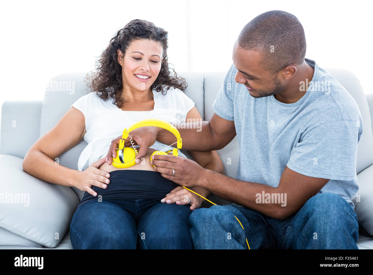 Cheerful man with headphones on pregnant belly Stock Photo Alamy