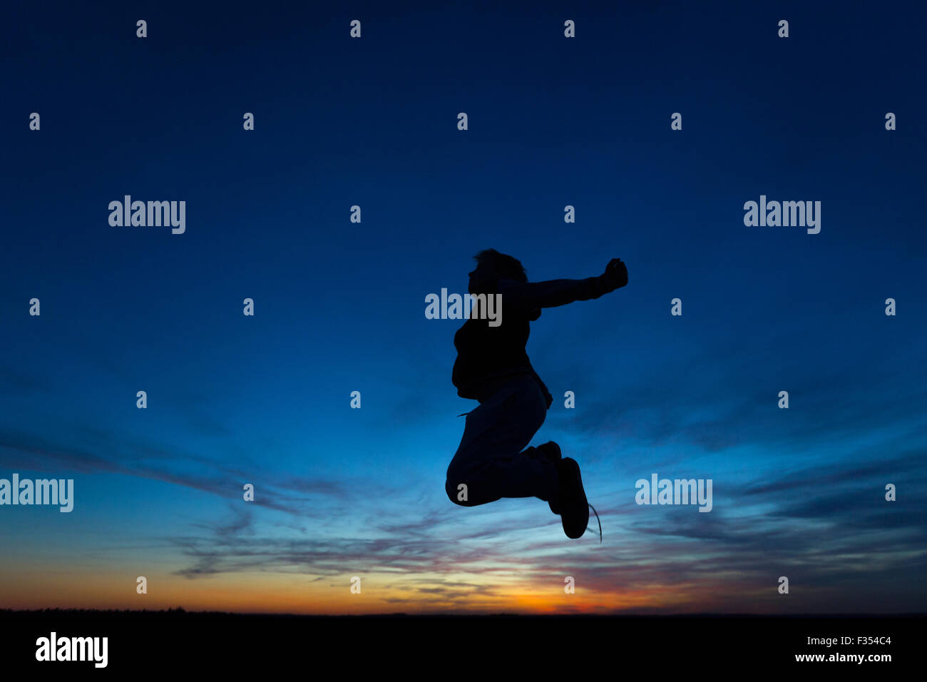 silhouette of a boy playing outside at dusk Stock Photo