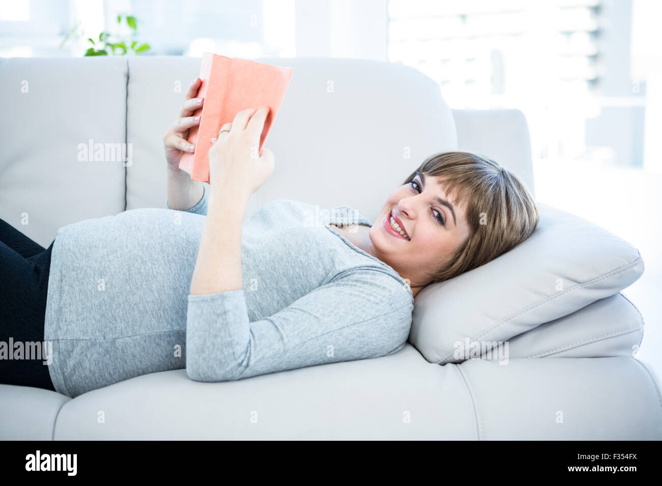 Portrait of happy woman reading book at home Stock Photo - Alamy