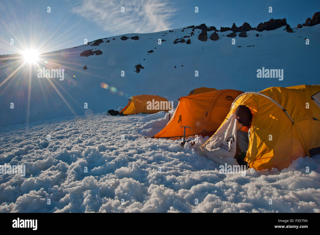 A climber watches the sun set over a ridge from a camp on Mount Shasta