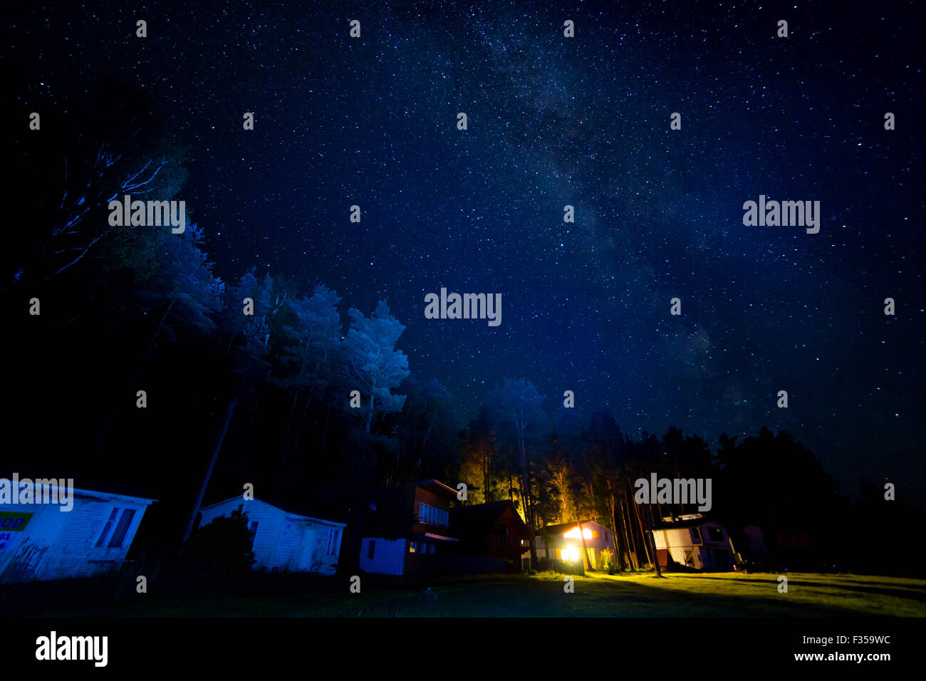 Night starry sky scene with milky way and lights of cottages Stock ...