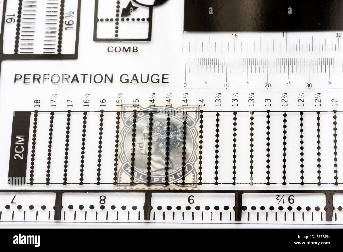 Philately, stamp collecting. A late Victorian grey half penny stamp under a transparent perforation gauge. Stock Photo