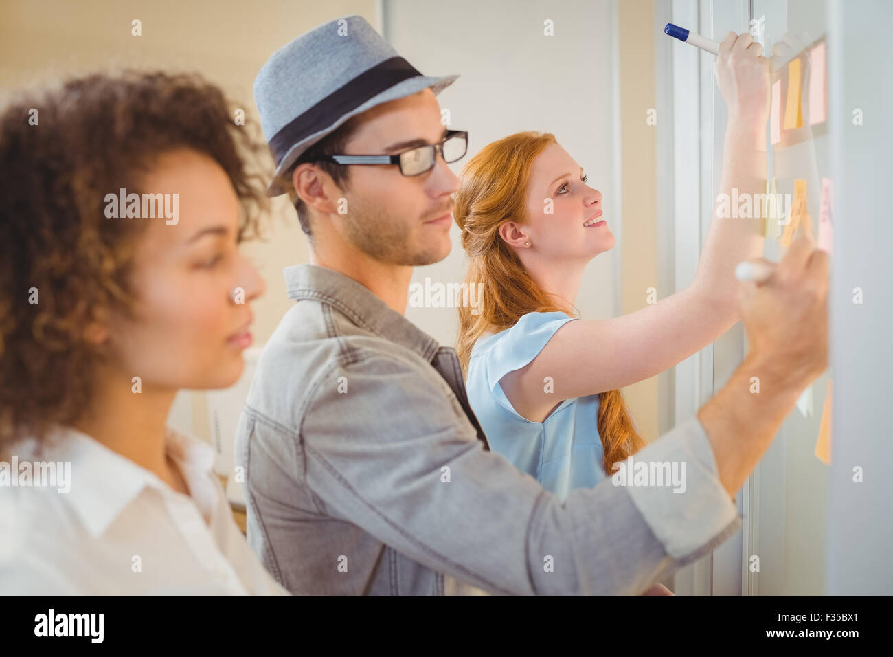 Business people writing on adhesive notes on glass wall Stock Photo