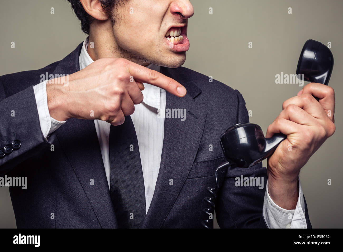 An angry young businessman is on the phone and screaming Stock Photo