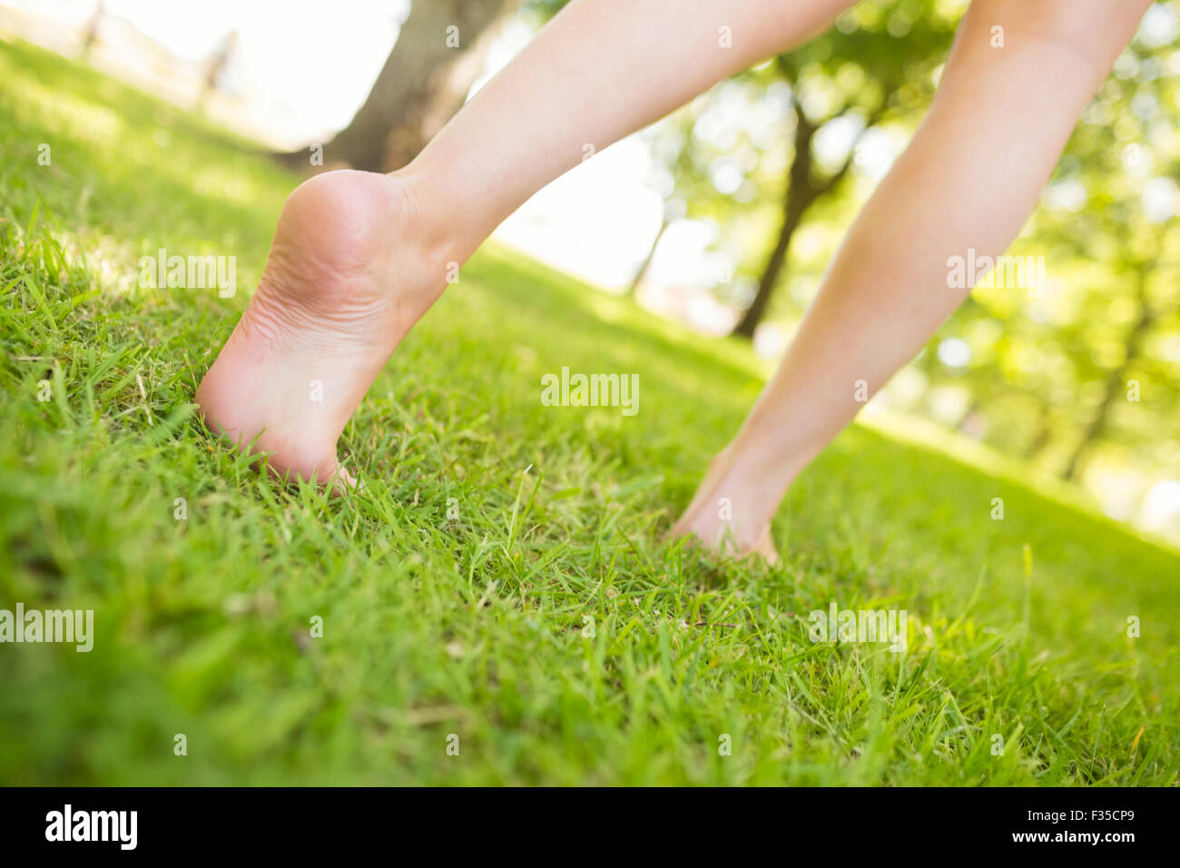 Low section of woman walking on grass Stock Photo