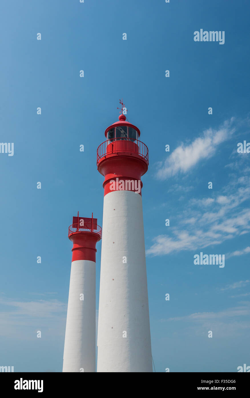 Two white and red lighthouses isolated on a blue and cloudy sky Stock Photo