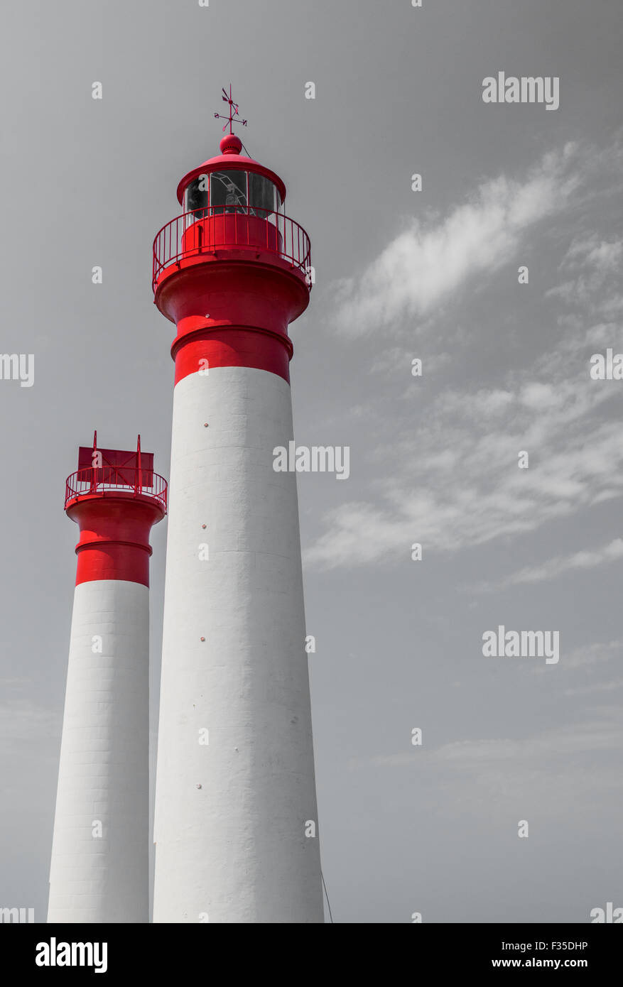 Two white and red lighthouses isolated on grey sky with clouds Stock Photo