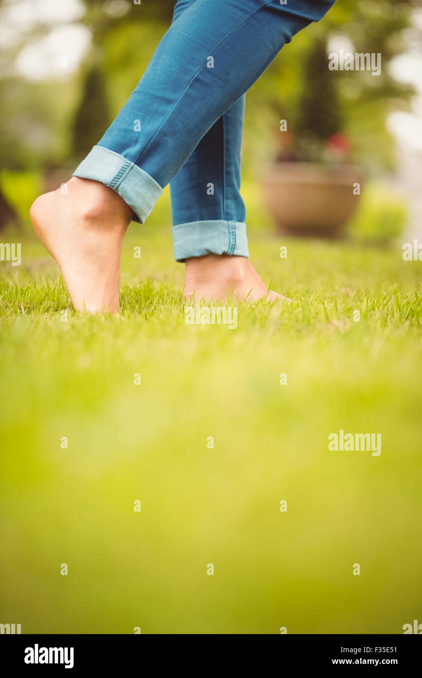 Low section of woman walking on green grass Stock Photo