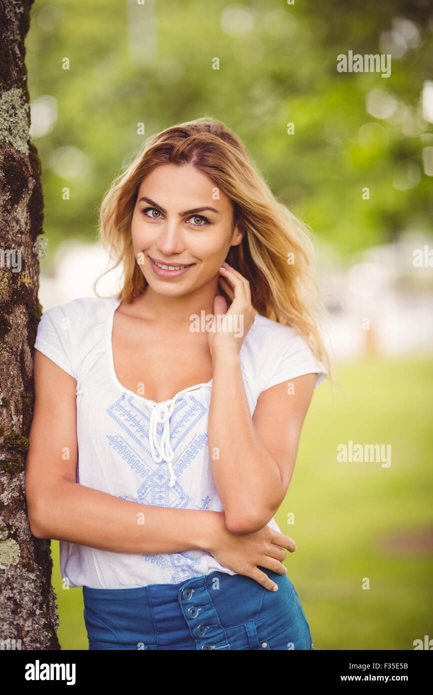 Portrait of smiling woman standing by tree Stock Photo - Alamy