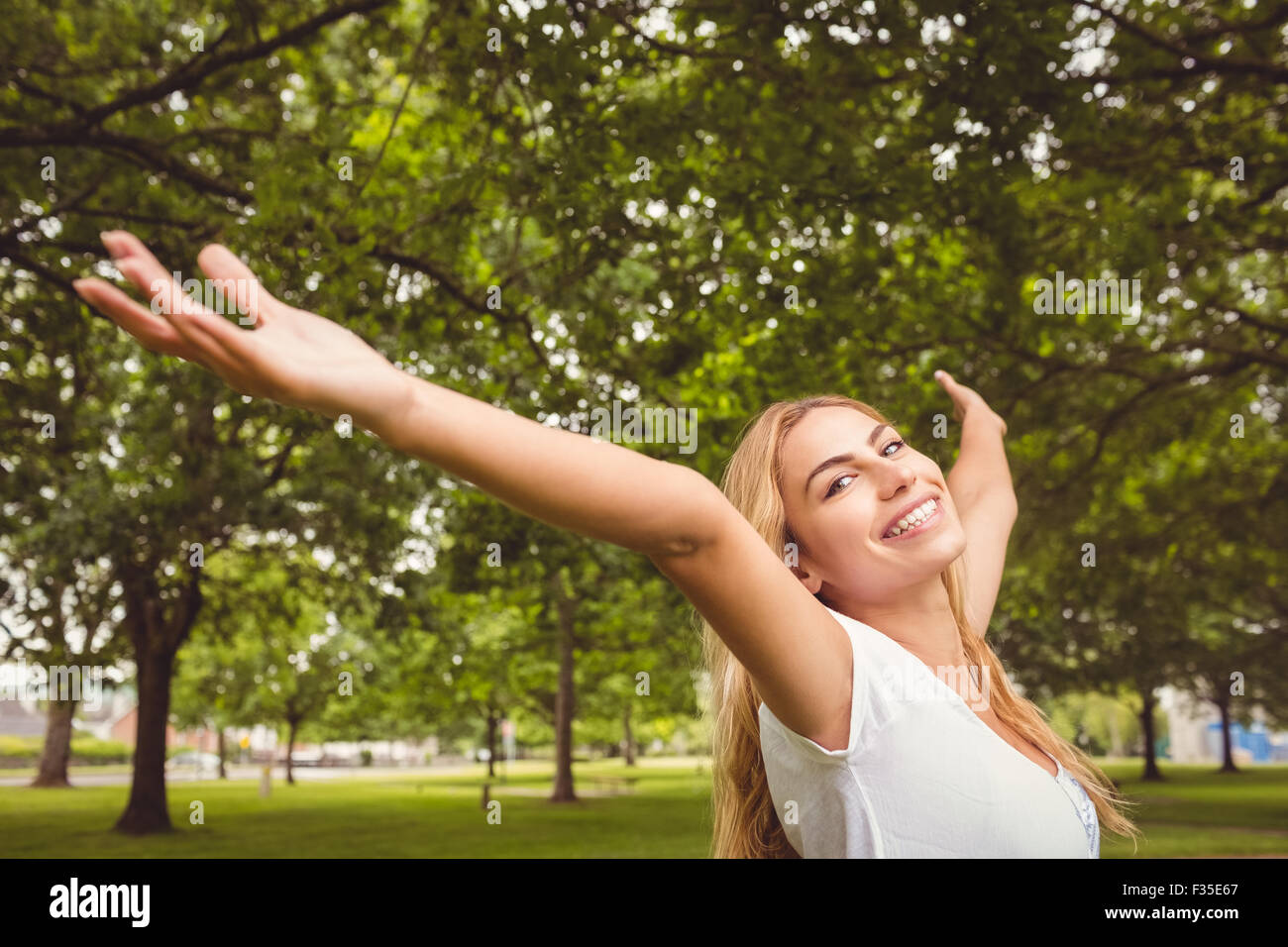 Portrait of smiling woman with arms raised in park Stock Photo - Alamy