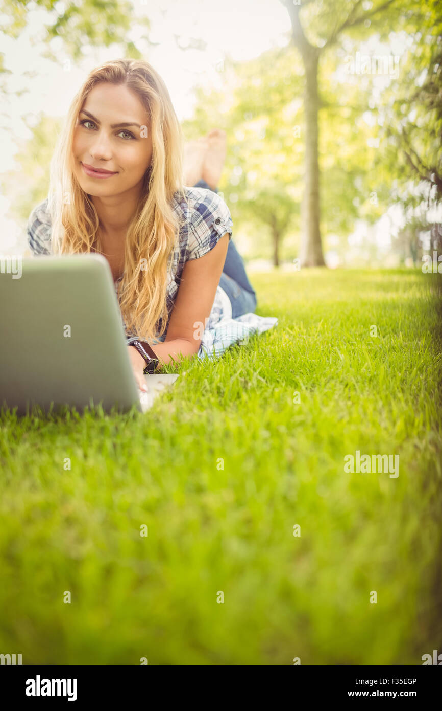 Portrait of smiling woman using laptop while lying on grass Stock Photo ...