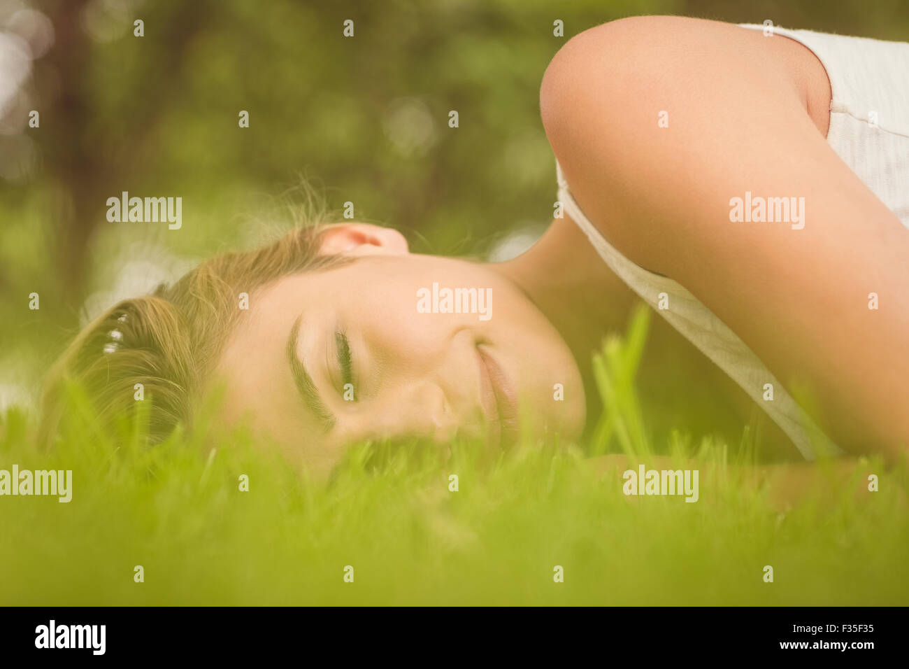 Beautiful woman with eyes closed while lying on grass Stock Photo - Alamy