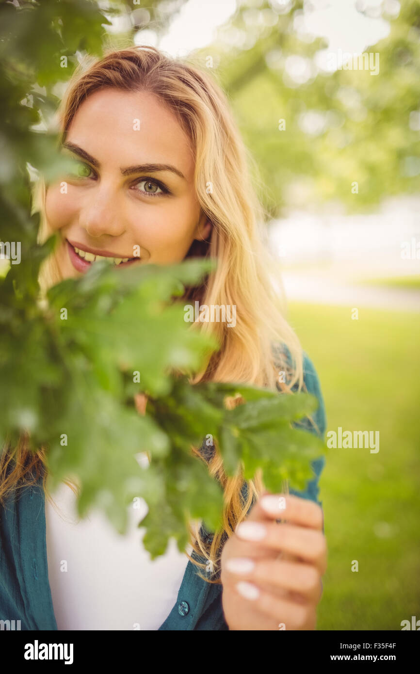 Portrait of smiling woman standing by tree at park Stock Photo - Alamy