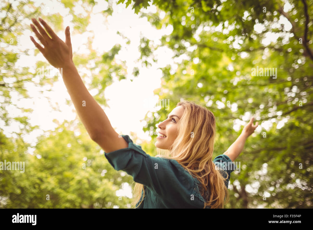 Beautiful smiling woman with arms raised at park Stock Photo - Alamy