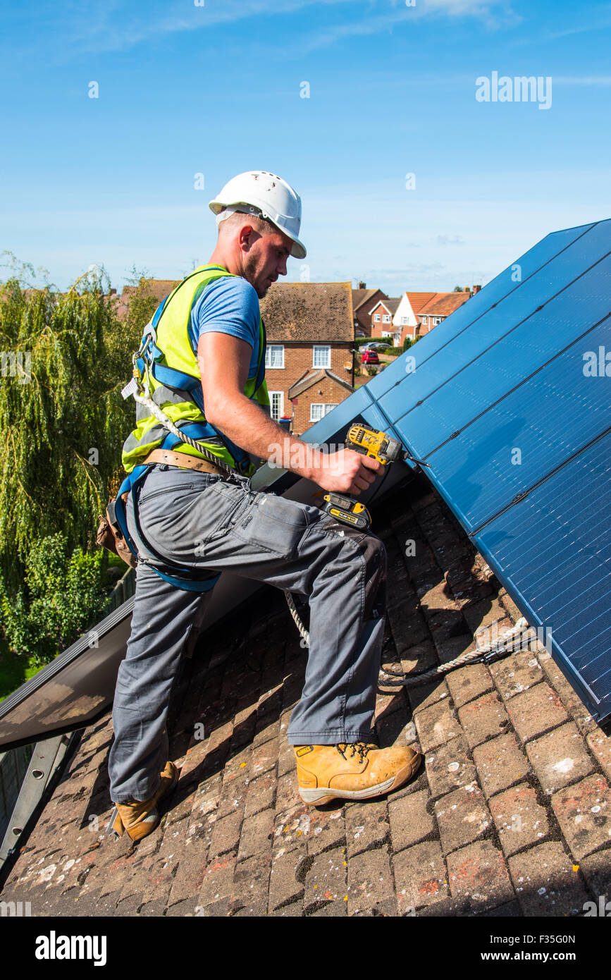 Roofer fitting a domestic solar panel system Stock Photo