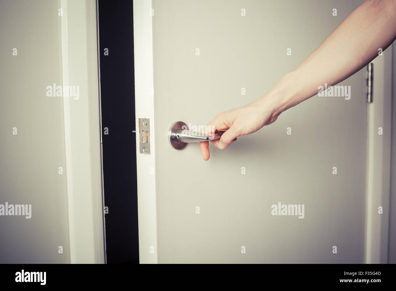 Closeup on the hand of a woman as she is opening a door at night Stock Photo