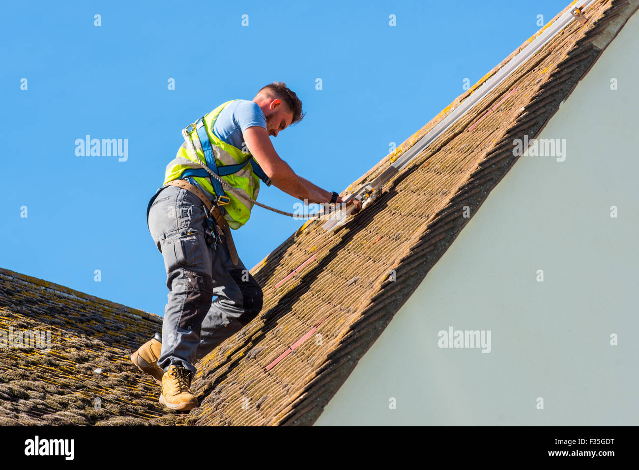 Roofer fitting supporting rail for a domestic solar panel system Stock