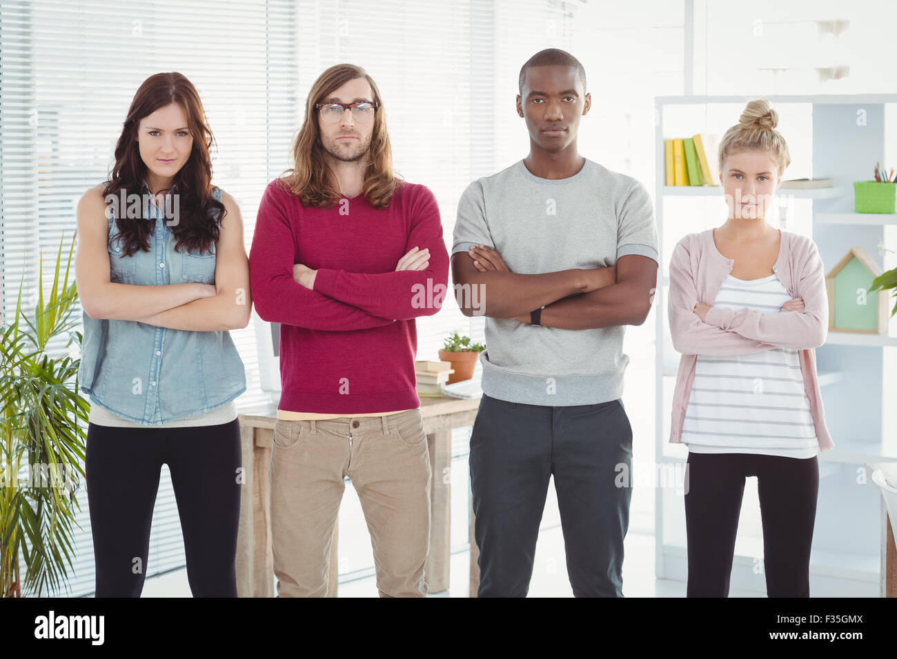 Portrait of business team with arms crossed while standing in a row ...