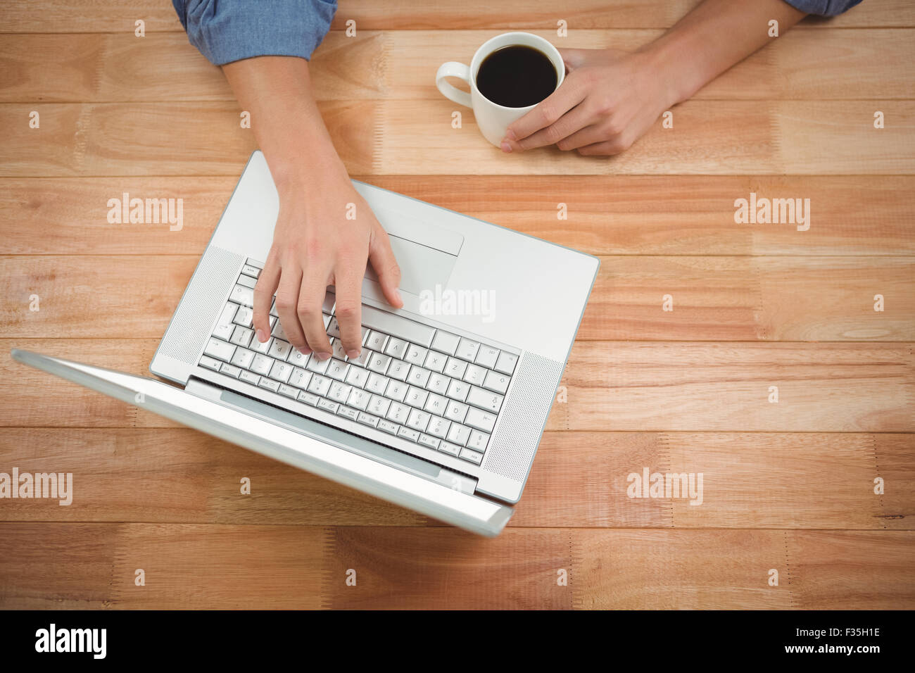 Man holding coffee while working on laptop Stock Photo