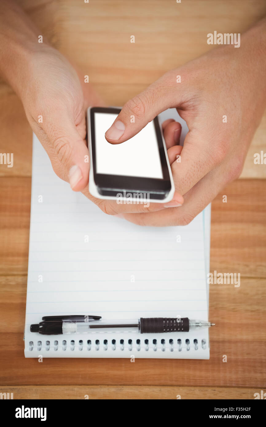 Man using smartphone with notepad on table in office Stock Photo
