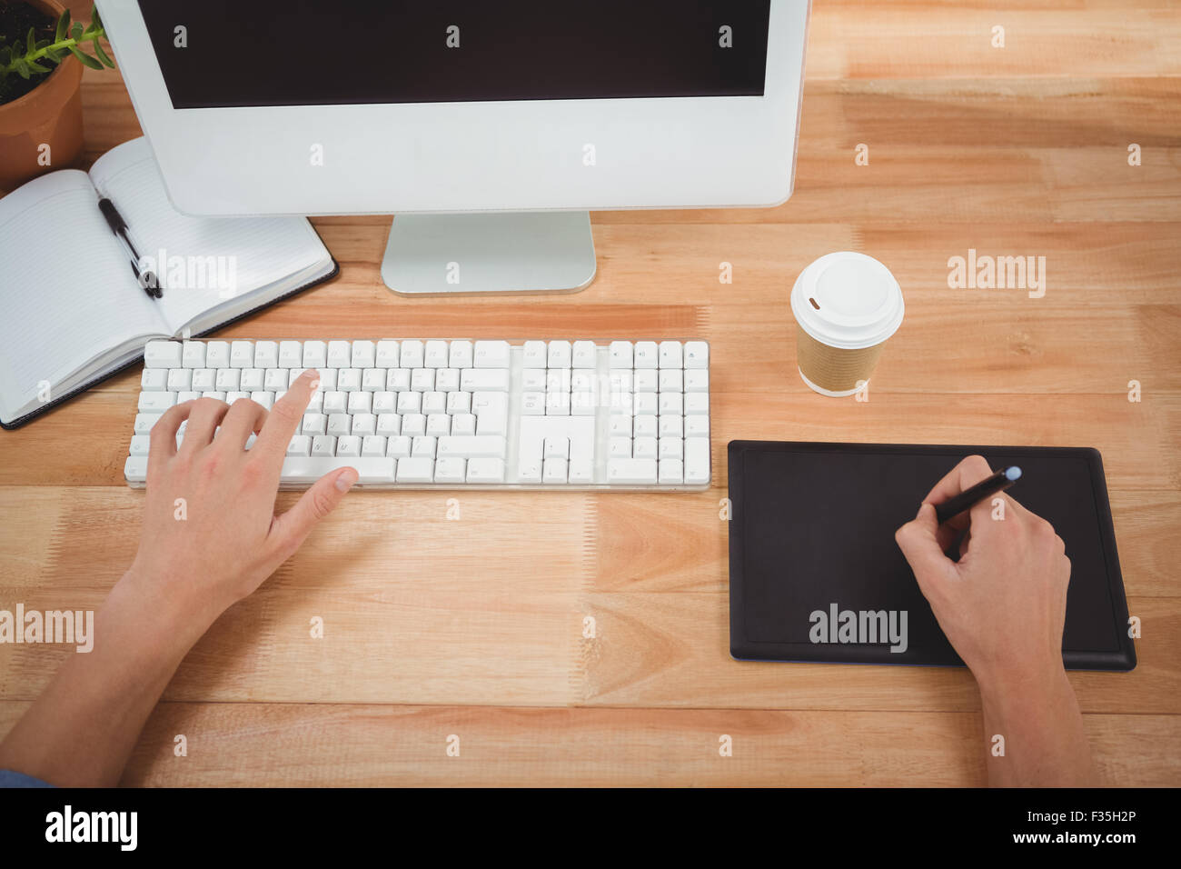 Man using graphics tablet while typing on keyboard Stock Photo
