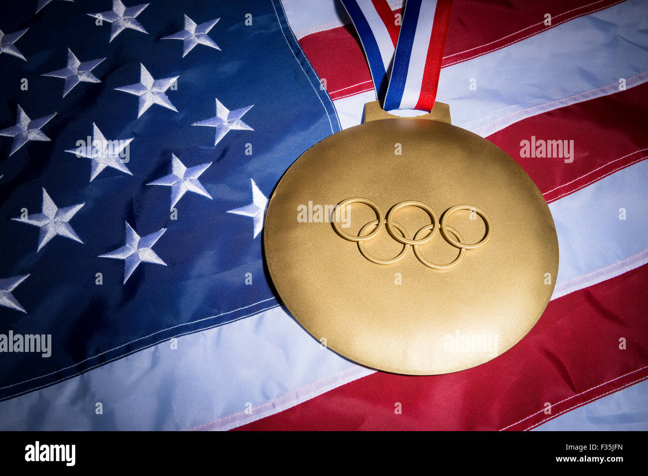 RIO DE JANEIRO, BRAZIL - FEBRUARY 3, 2015: Large gold medal featuring Olympic rings sits on American flag background. Stock Photo