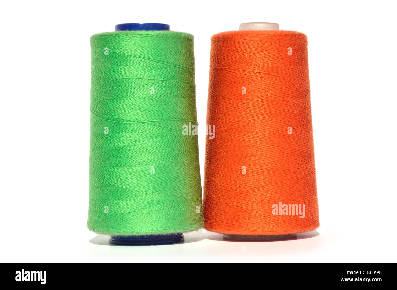 Reels of green and orange thread on white background Stock Photo - Alamy