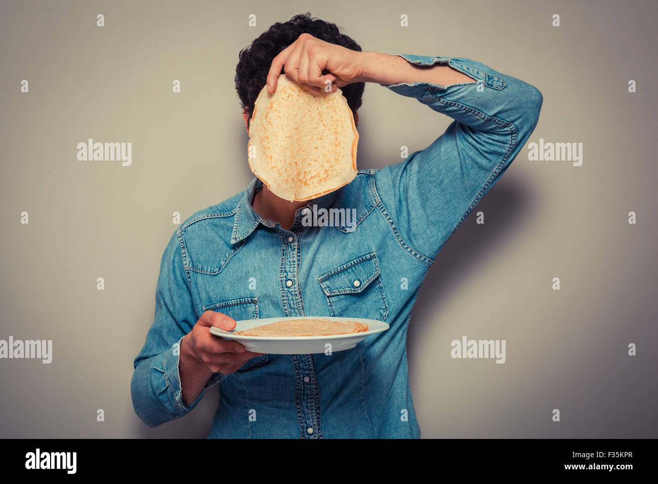 Young man is hiding his face behind a pancake Stock Photo Alamy