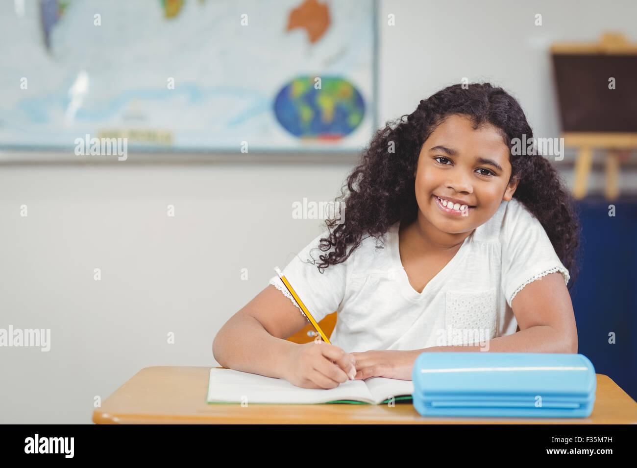 Smiling pupil working at her desk in a classroom Stock Photo - Alamy