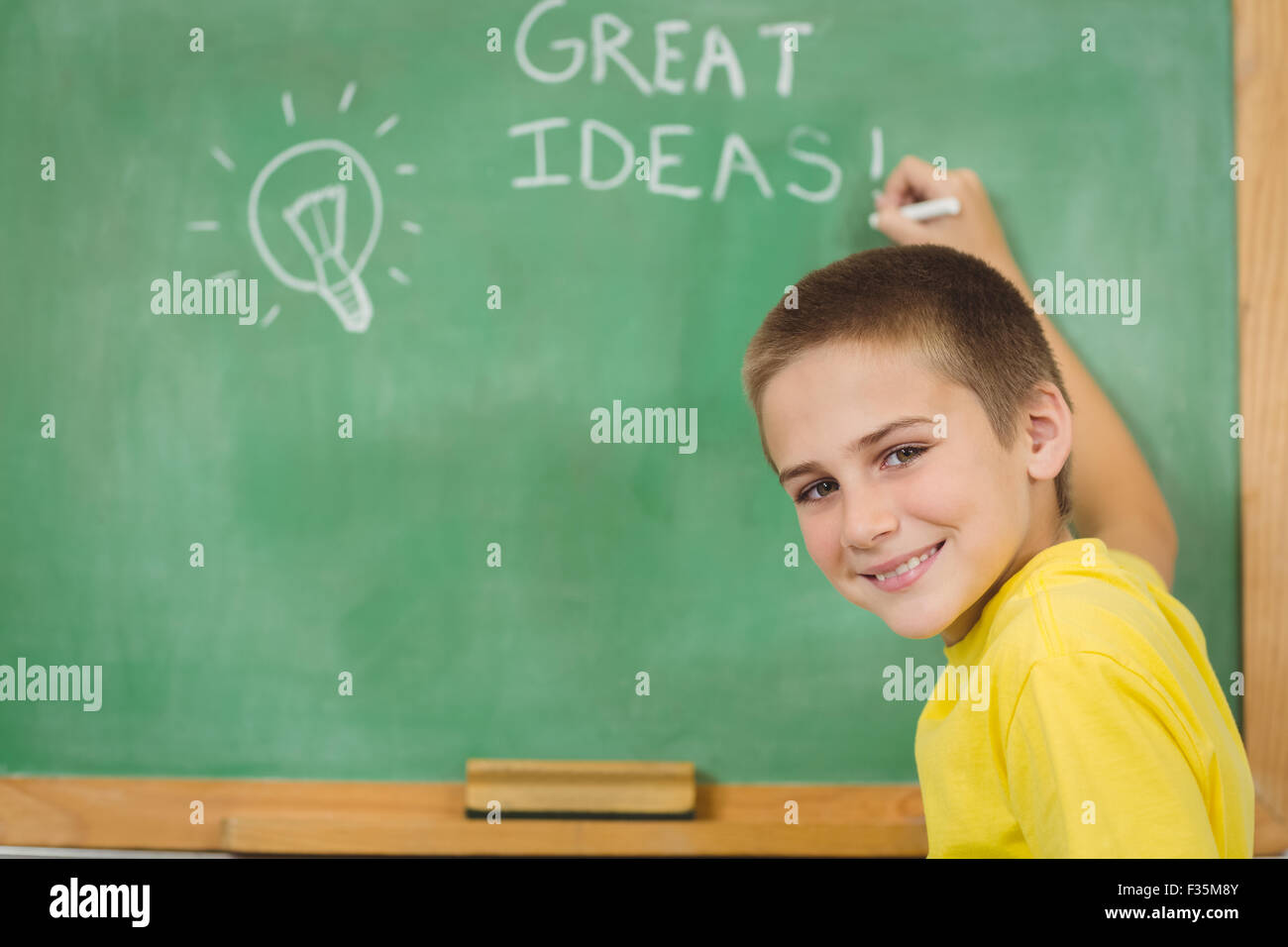 Smiling pupil writing on chalkboard in a classroom Stock Photo - Alamy