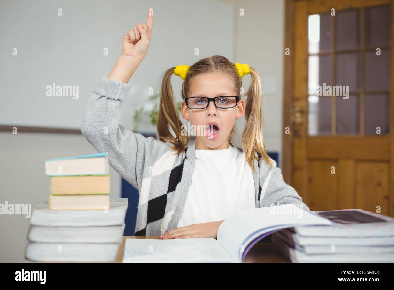 Pupil sitting at her desk and having a question Stock Photo - Alamy